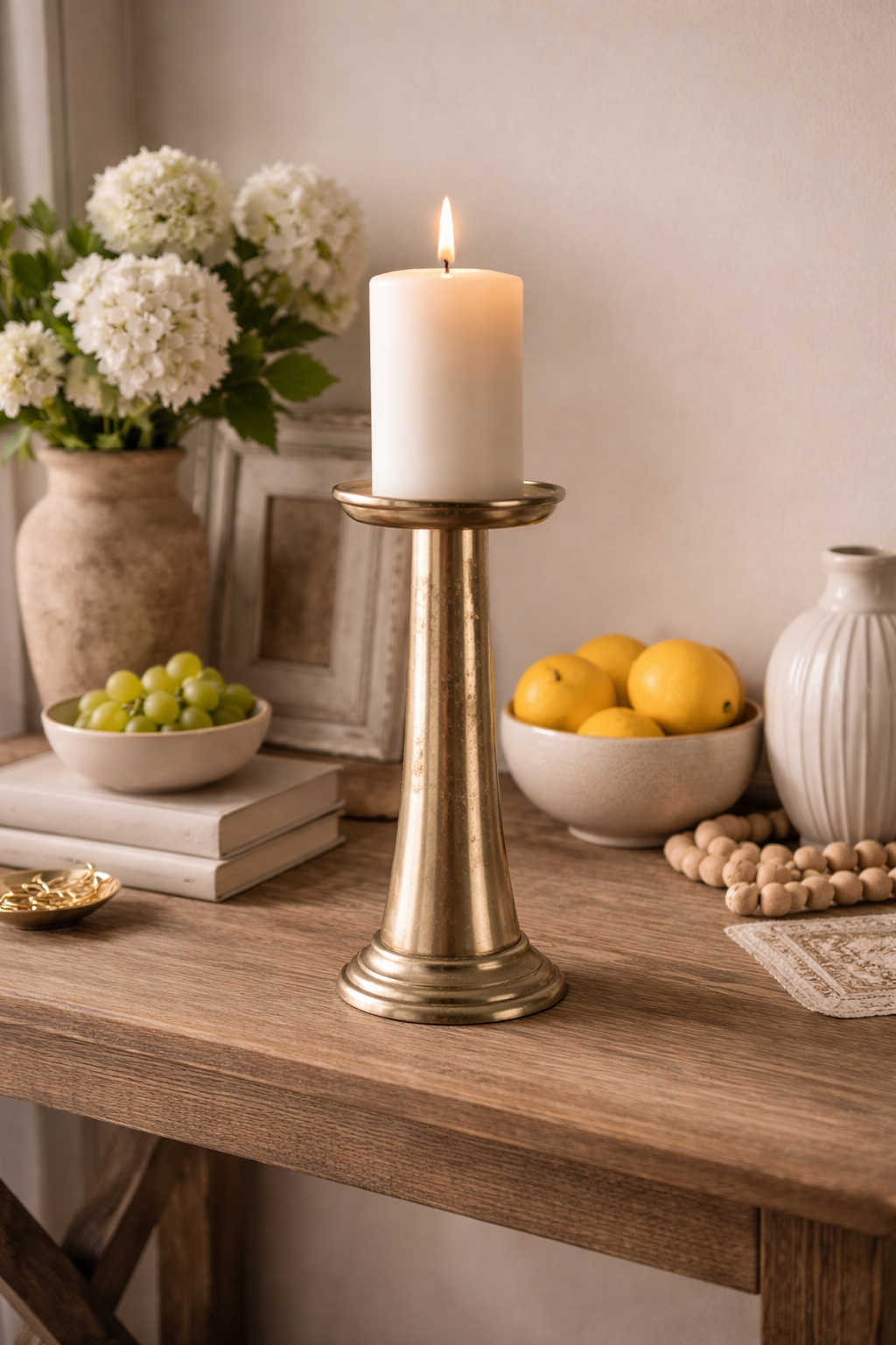 Candle on a brass holder with decorative items on a wooden table