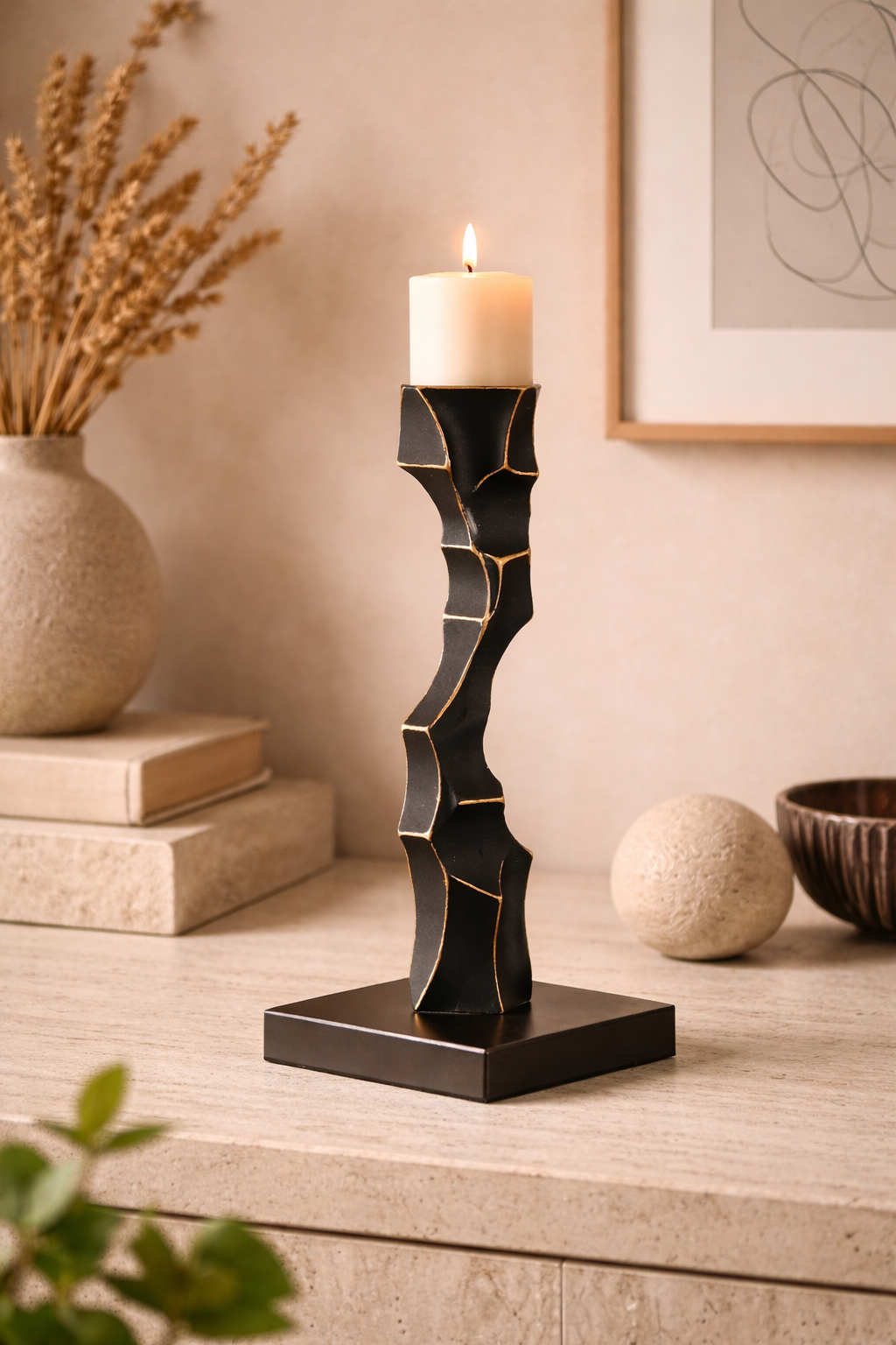 Decorative candle holder with a candle on a wooden surface, surrounded by books and a vase.