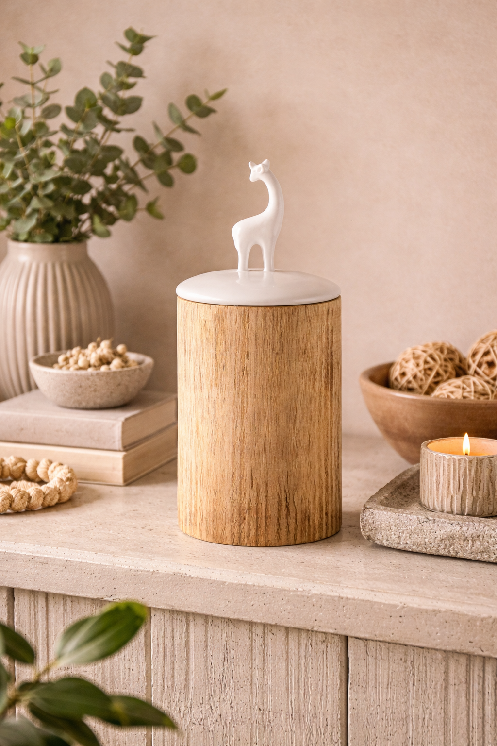 Decorative wooden candle holder with a white figurine on top, placed on a surface with books and plants.
