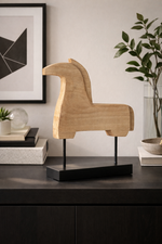 Wooden horse sculpture on a black base in a modern interior setting