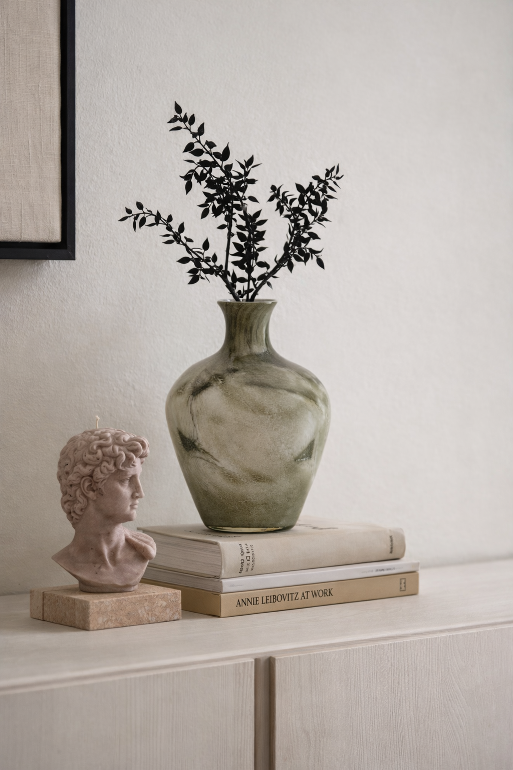Decorative items including a vase with greenery, a classical bust, and books on a shelf.