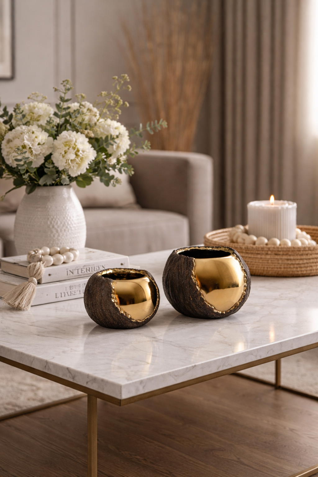 Decorative items on a marble table including vases, candles, and books with a neutral background.