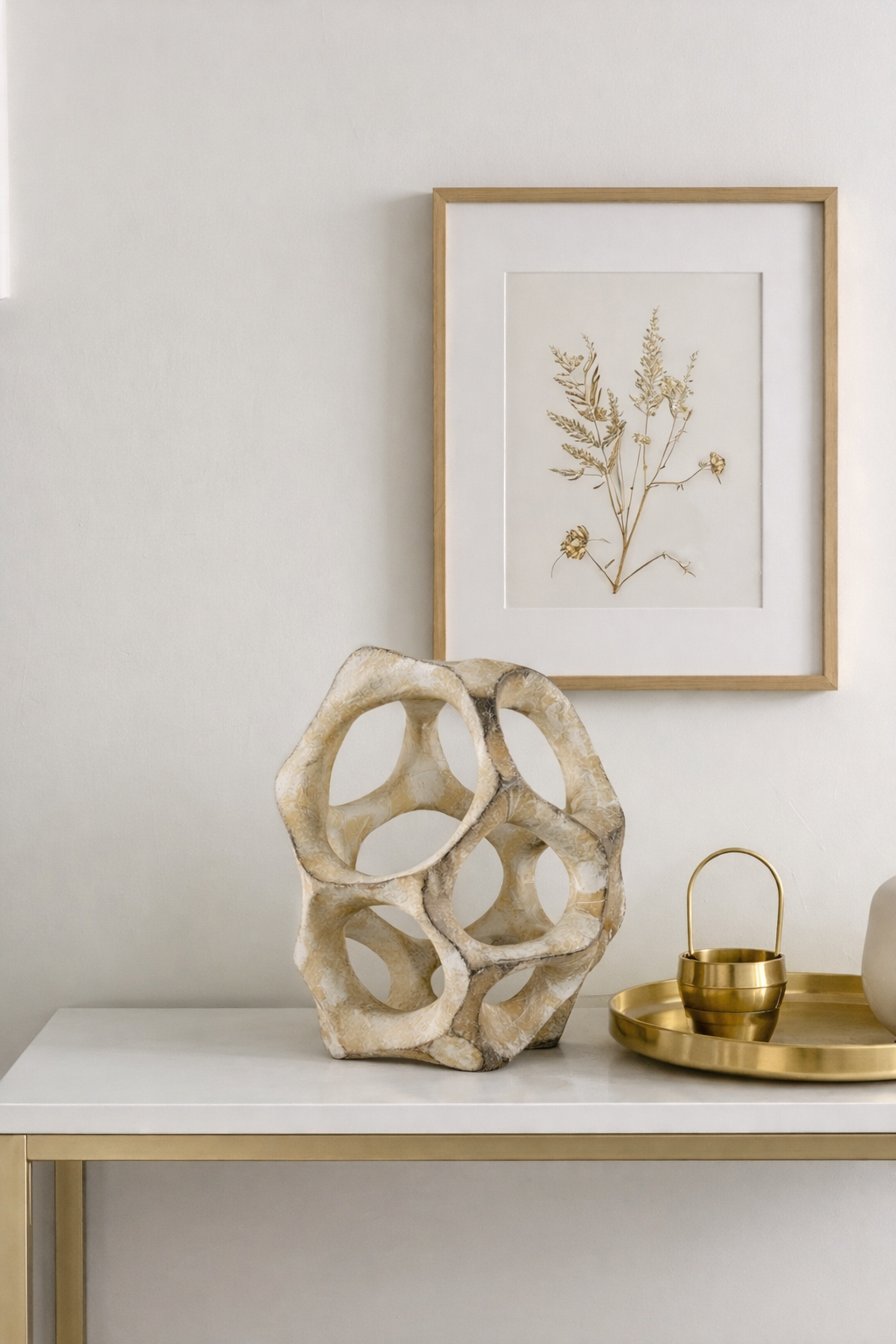 Decorative table with a textured vase, framed artwork, and gold accents.