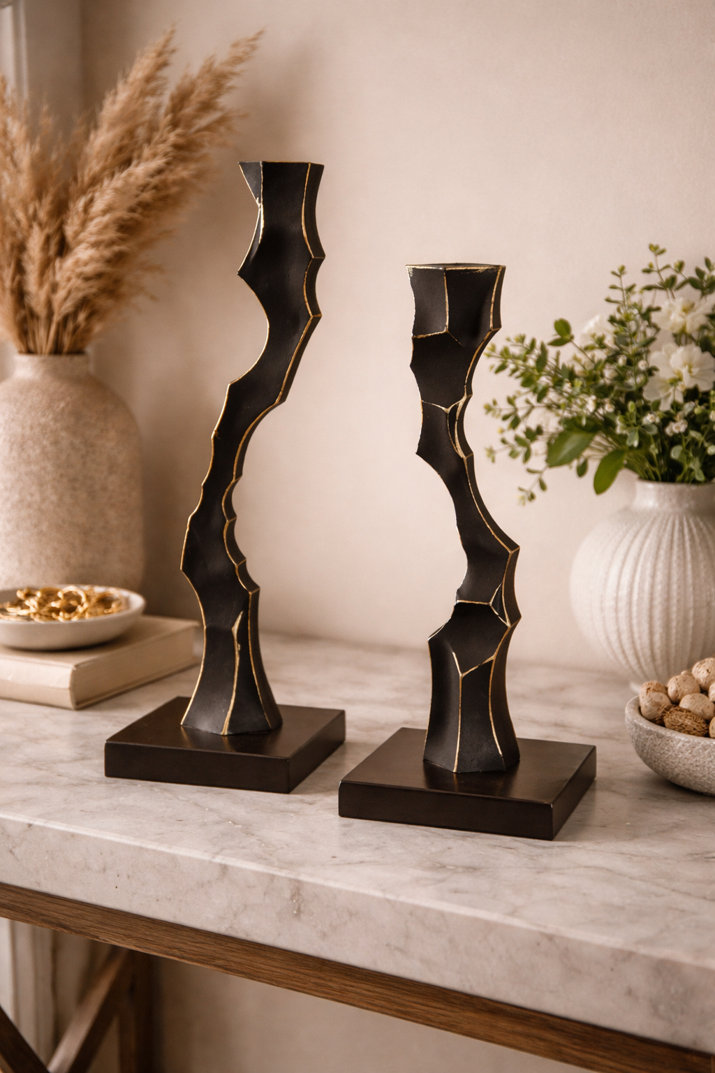 Two decorative candle holders on a marble surface with a neutral background