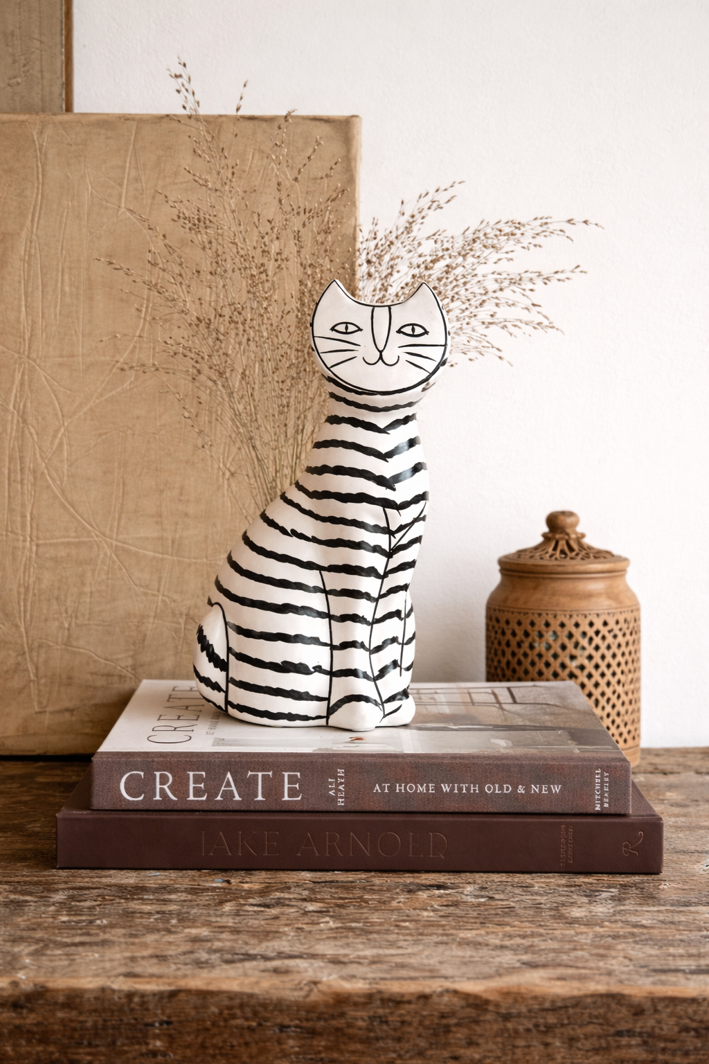 Decorative cat figurine on top of books with a wicker basket in the background