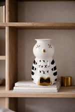 Decorative owl-shaped lamp on a shelf with books and a small gold container.
