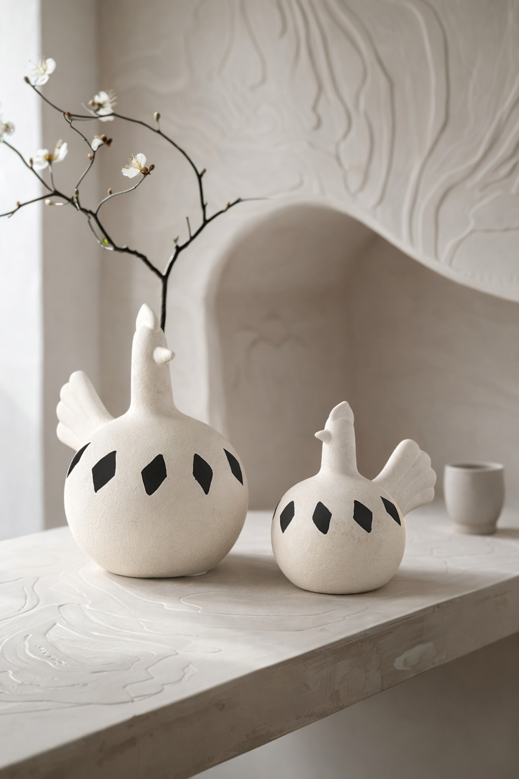 Two white ceramic birds with black spots on a light wooden surface.