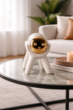 Ceramic astronaut figurine on a glass coffee table in a living room setting.