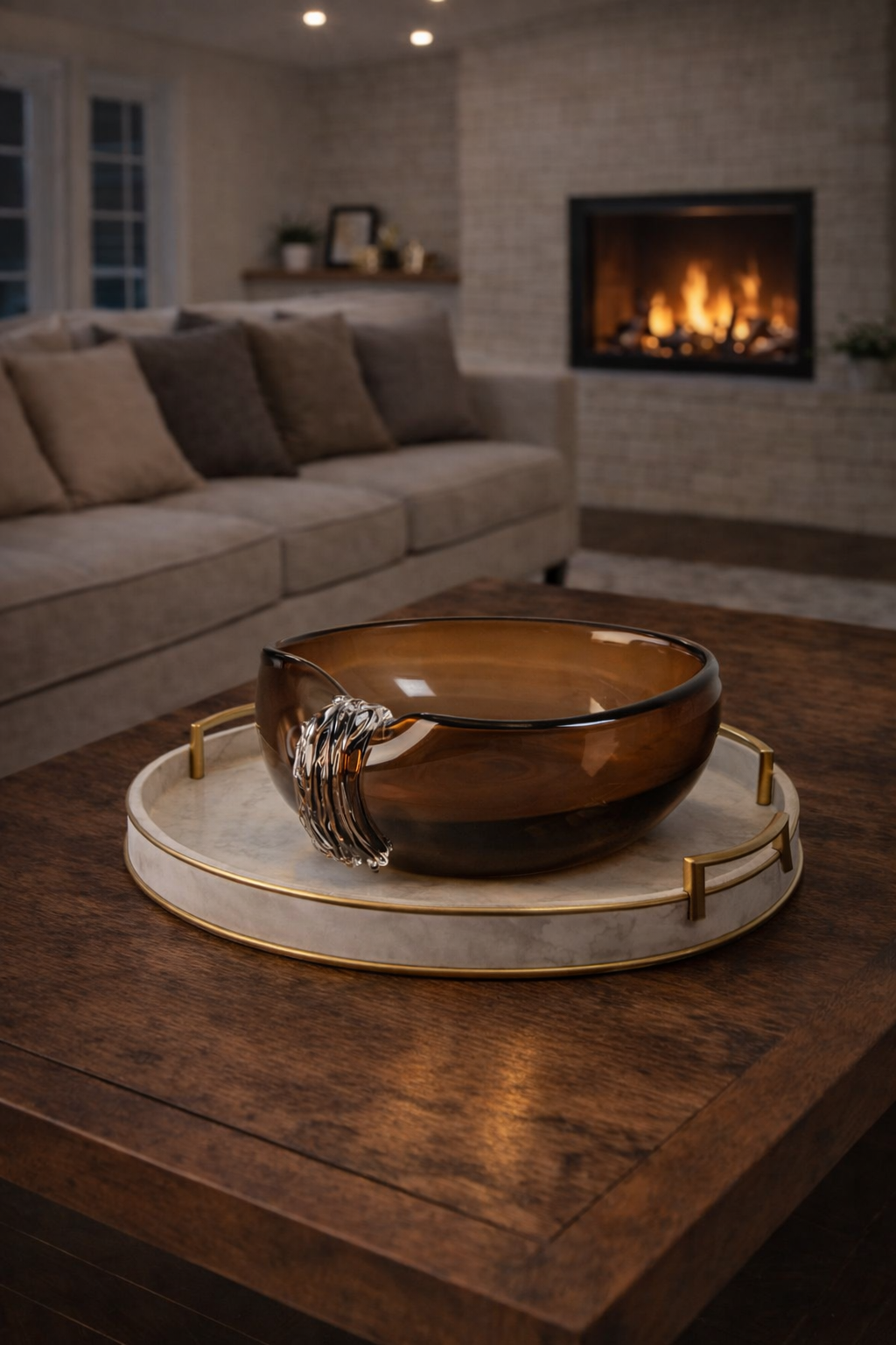 Brown glass bowl on a marble tray with a fireplace and sofa in the background