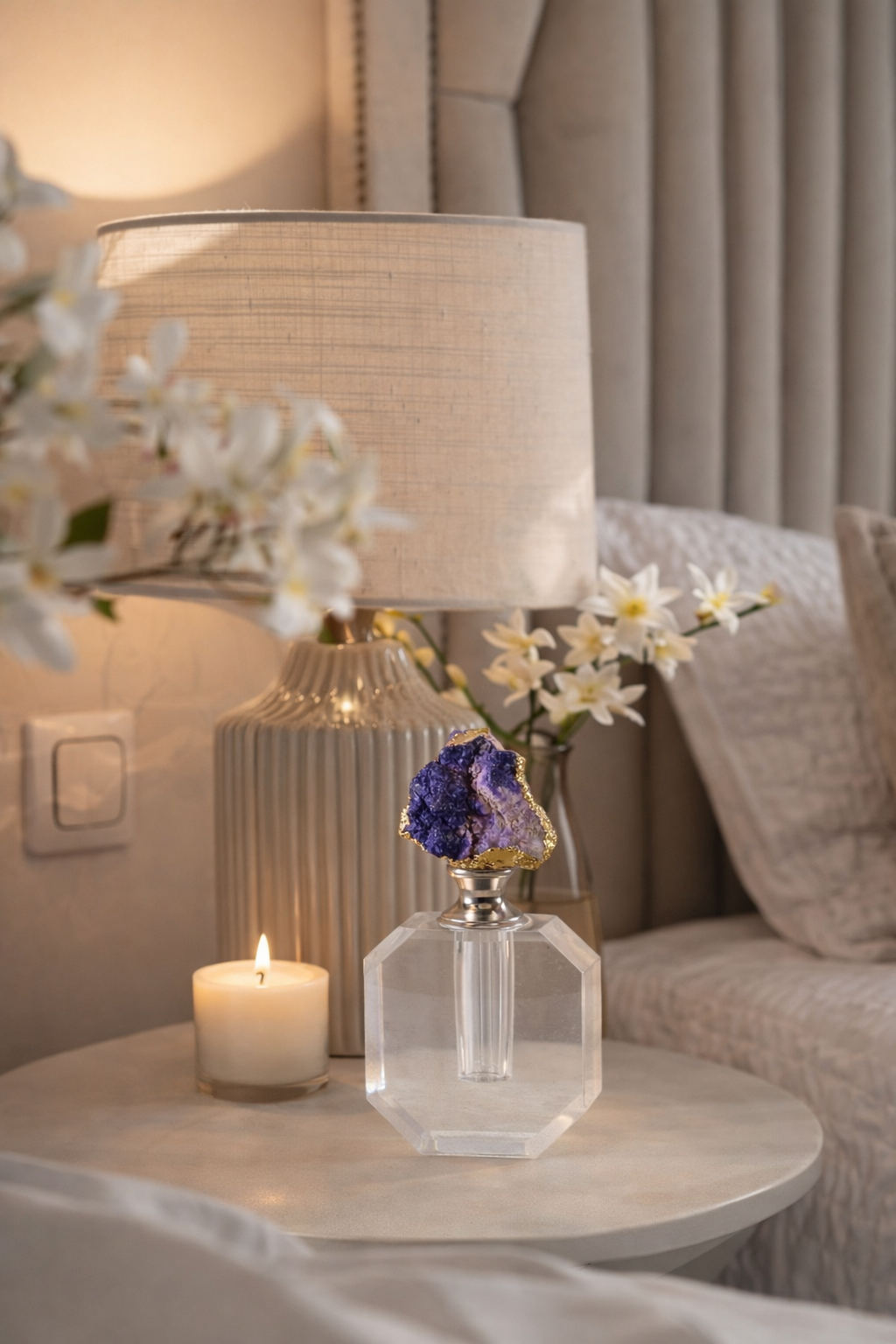 Decorative table with a crystal vase, candle, and flowers in a living room setting.