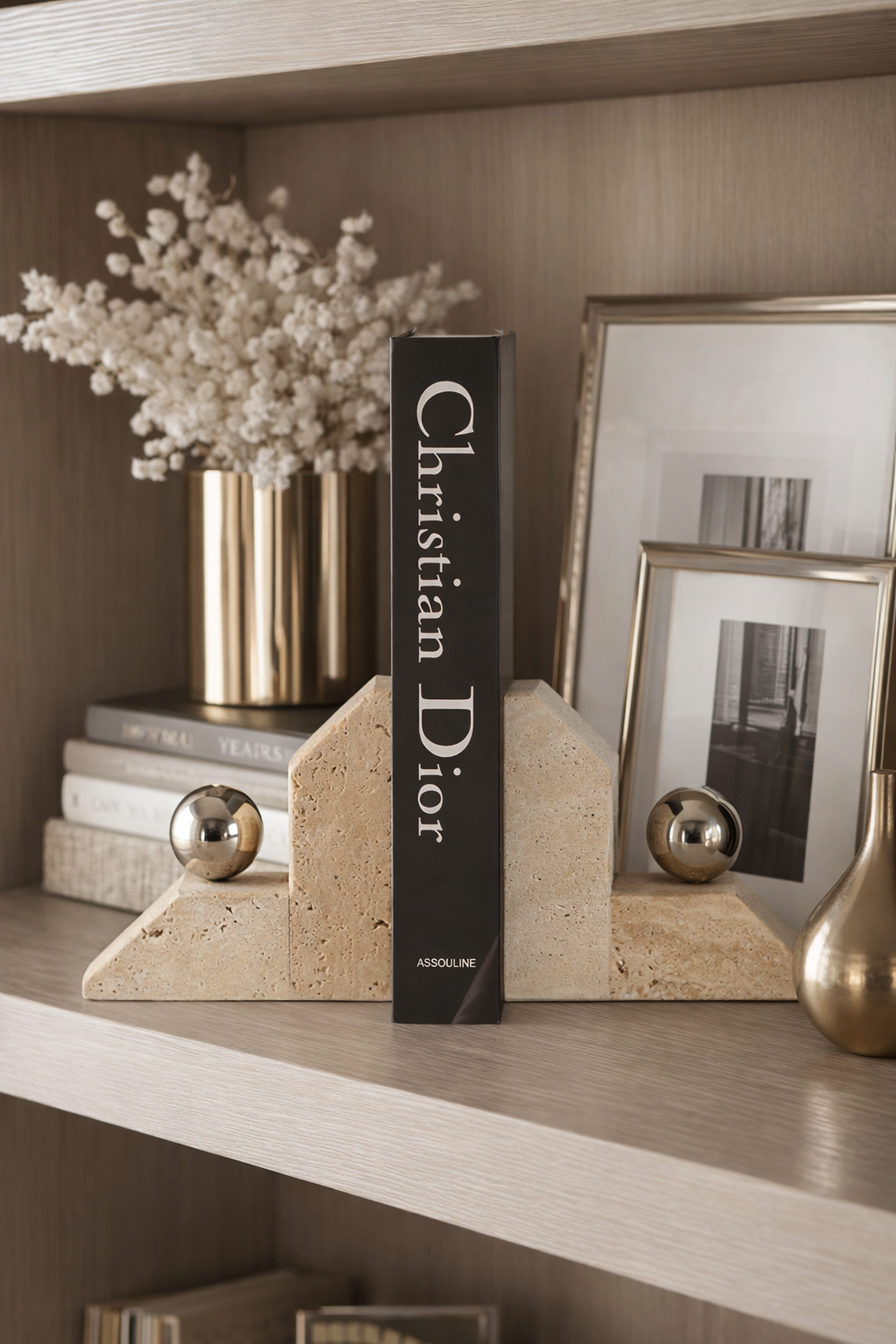 Decorative shelf with books, a vase of flowers, and framed pictures.
