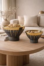 Two decorative bowls with gold accents on a wooden coffee table in a living room setting.