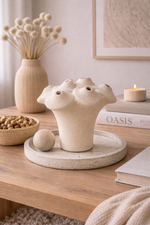 Decorative ceramic vase on a wooden table with books and a candle in the background