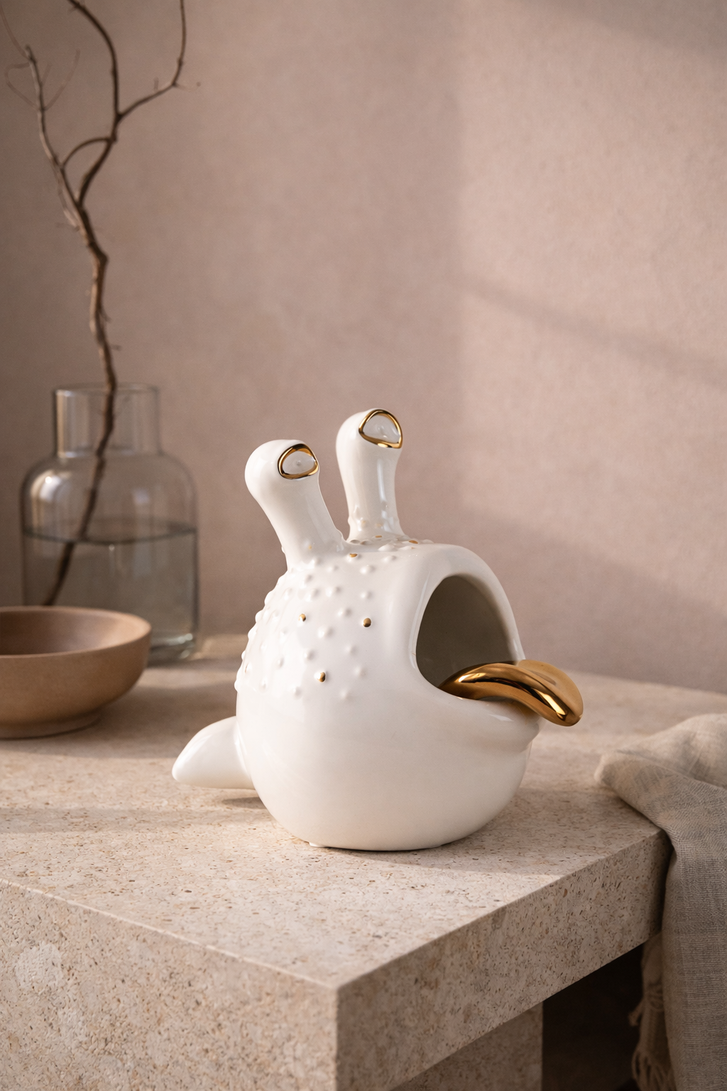 White ceramic teapot with gold accents on a stone surface