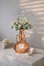 Copper vase with flowers on a marble surface
