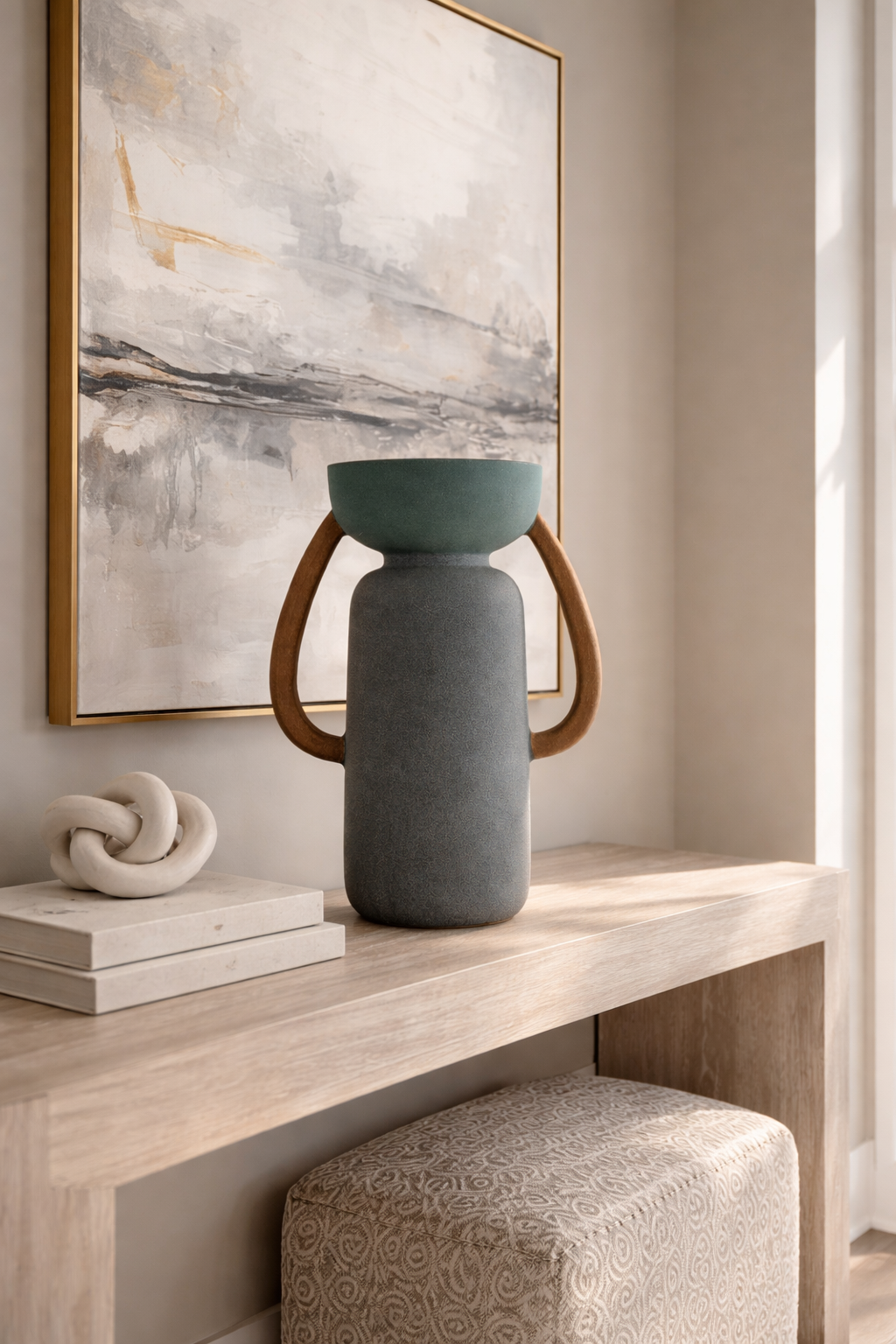 Gray vase with wooden handles on a wooden surface, abstract painting in the background