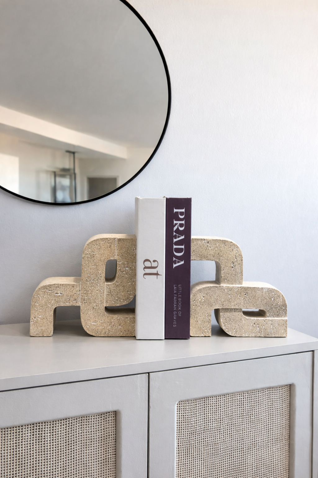 Decorative letter sculptures with a Prada book on a shelf in a modern interior setting.