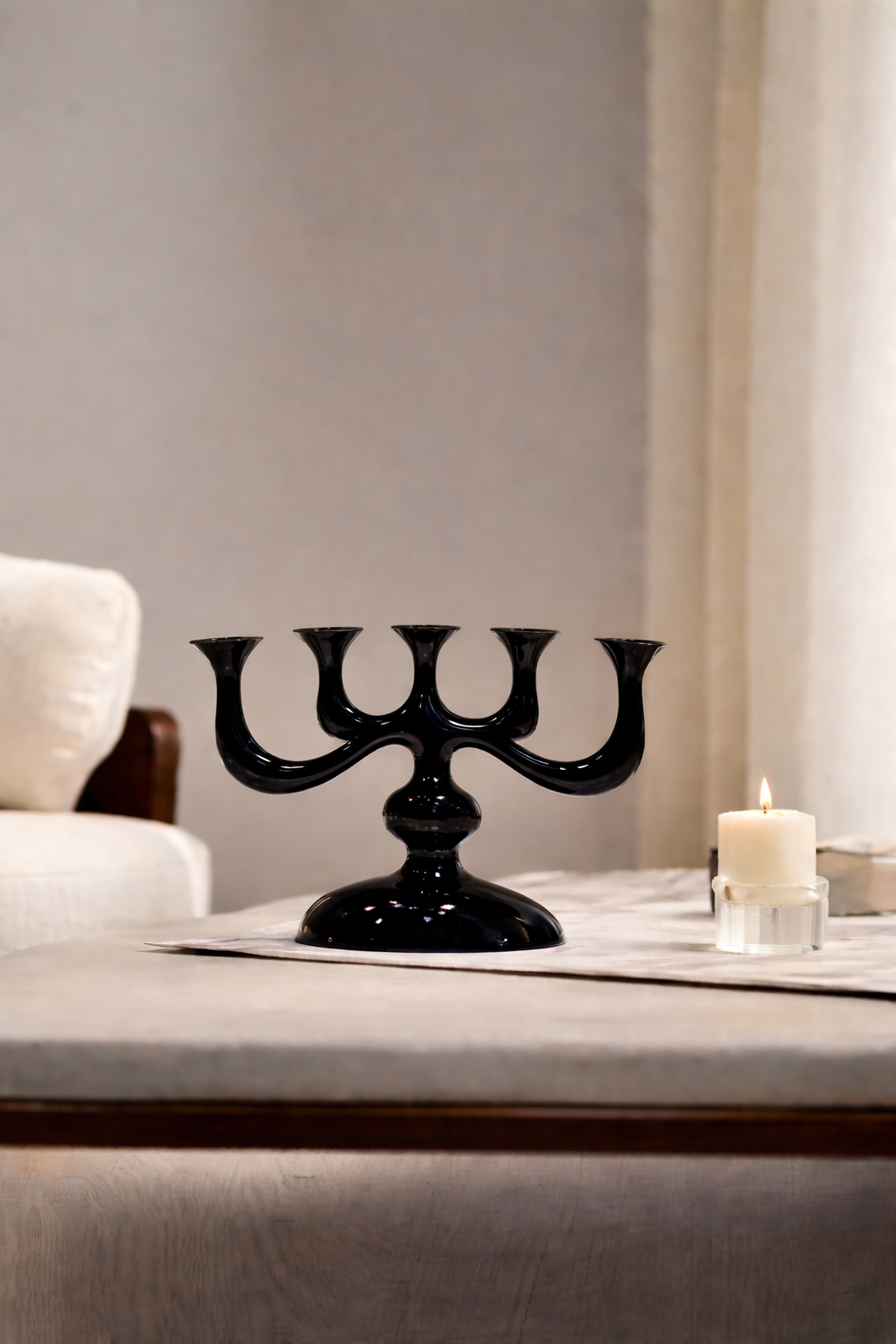 Black candelabra on a table with a candle in a room setting