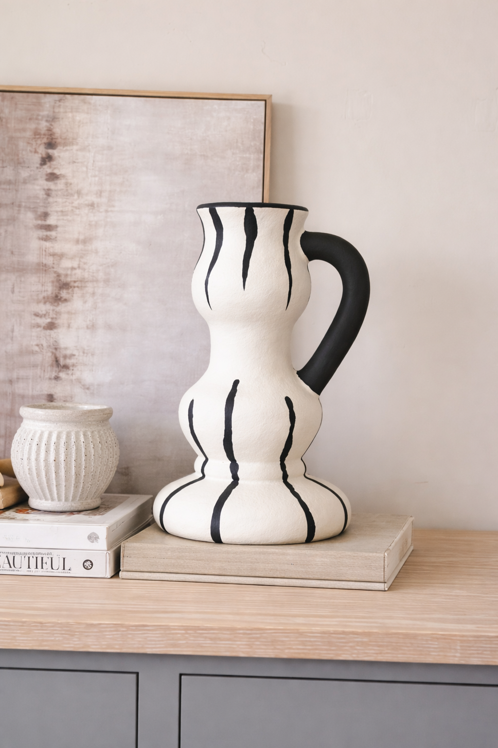 Black and white ceramic pitcher on a wooden surface with a neutral background