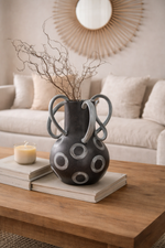 Decorative vase with circular patterns on a wooden table in a living room setting.