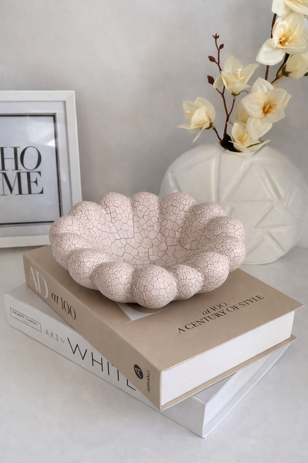 Decorative bowl on books with a vase of flowers in the background