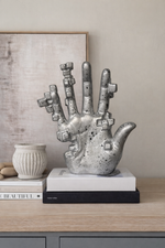 Decorative sculpture of a hand on books with a neutral background