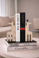Decorative bookends with Gucci, Chanel, and Christian Dior books on a table.