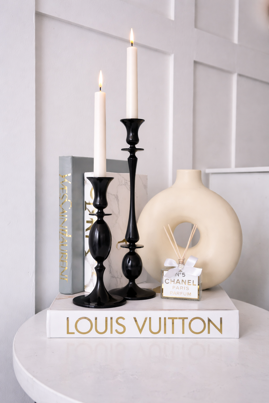 Decorative items including candles, a vase, and a book on a white surface with a light gray wall background.