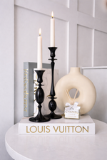 Decorative items including candles, a vase, and a book on a white surface with a light gray wall background.