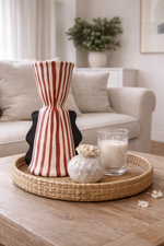 Decorative items on a coffee table including a striped vase, glass candle holder, and small white ornament.