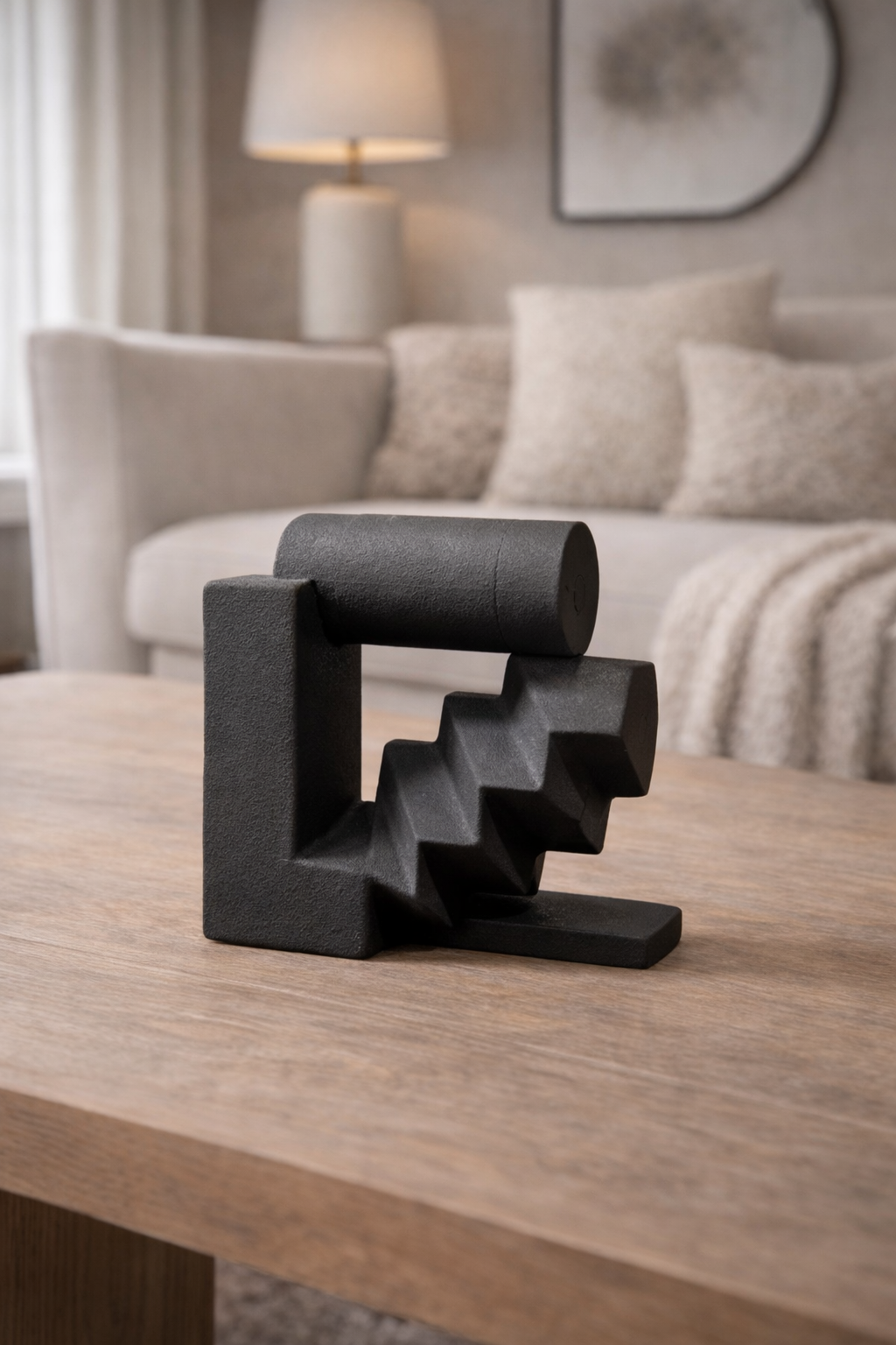 Black geometric sculpture on a wooden table with a living room background