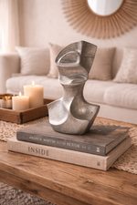Abstract sculpture on books with candles and a mirror in the background