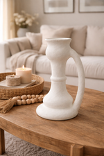 White candle holder on a wooden coffee table with a cozy living room background