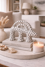 Decorative polka dot animal figurine on books with a candle and dried plants in a home setting