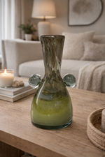 Decorative glass vase on a wooden table with a cozy living room background