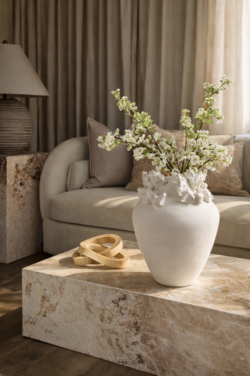 Living room with a beige sofa, decorative vase with flowers, and lamp.