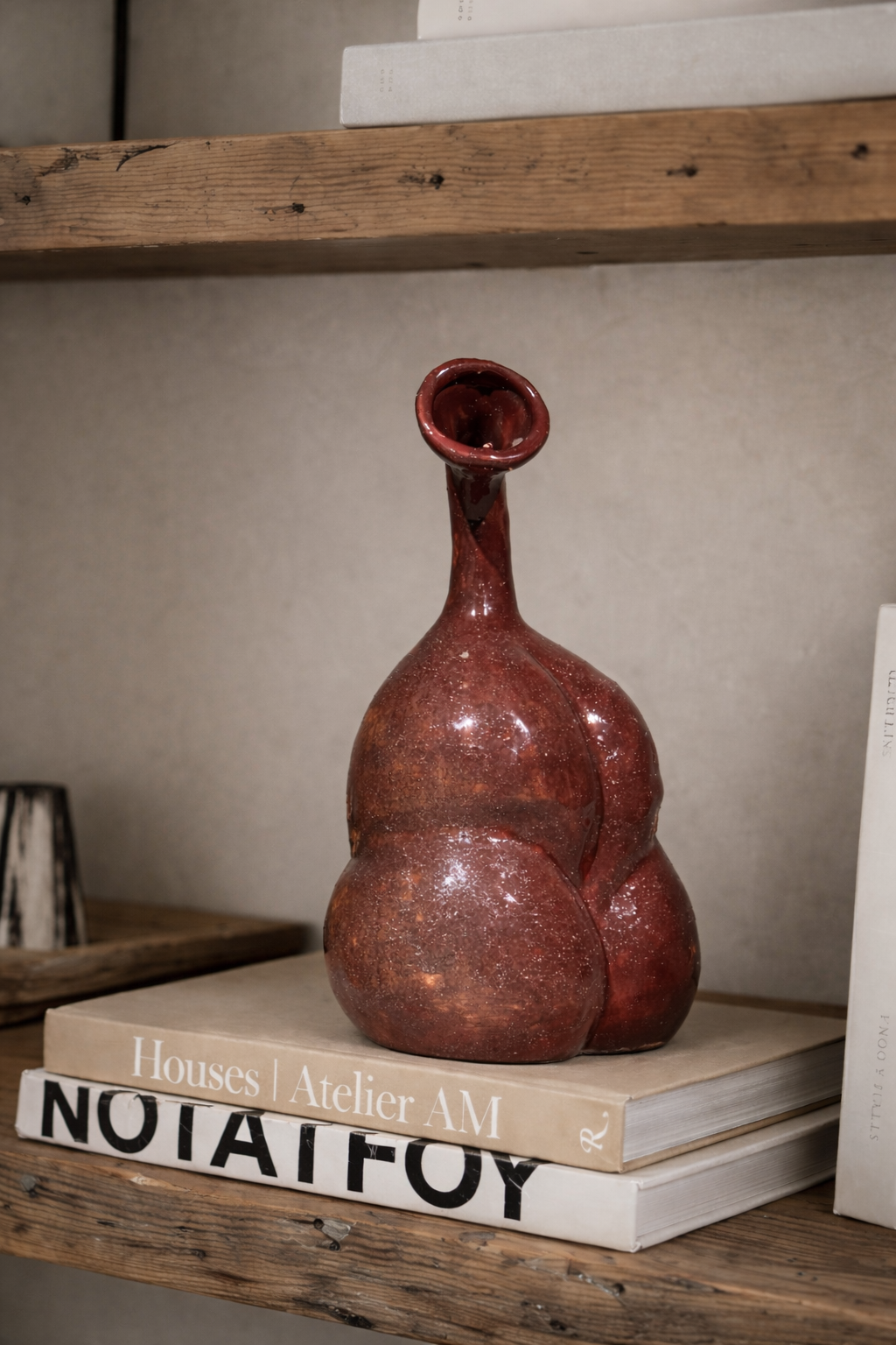 Decorative brown vase on a stack of books with a wooden shelf background