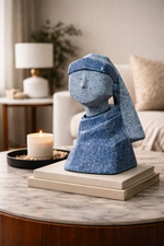 Blue stone sculpture on a marble surface with a candle and lamp in the background
