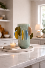 Decorative ceramic vase with abstract design on a marble countertop in a kitchen.