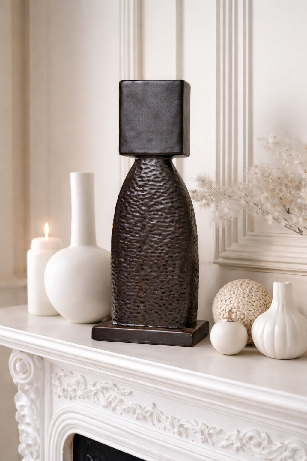 Decorative lamp with textured design on a white mantelpiece with other decorative items.