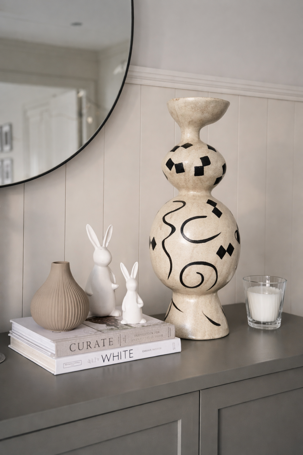 Decorative items on a shelf including a large vase, small vases, and books with a candle.