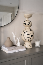 Decorative items on a shelf including a large vase, small vases, and books with a candle.