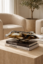Decorative sculpture on books with a blurred background of a living room.
