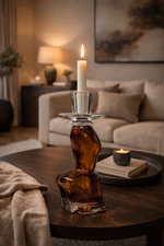 Candle holder with a candle on a wooden table in a cozy living room.