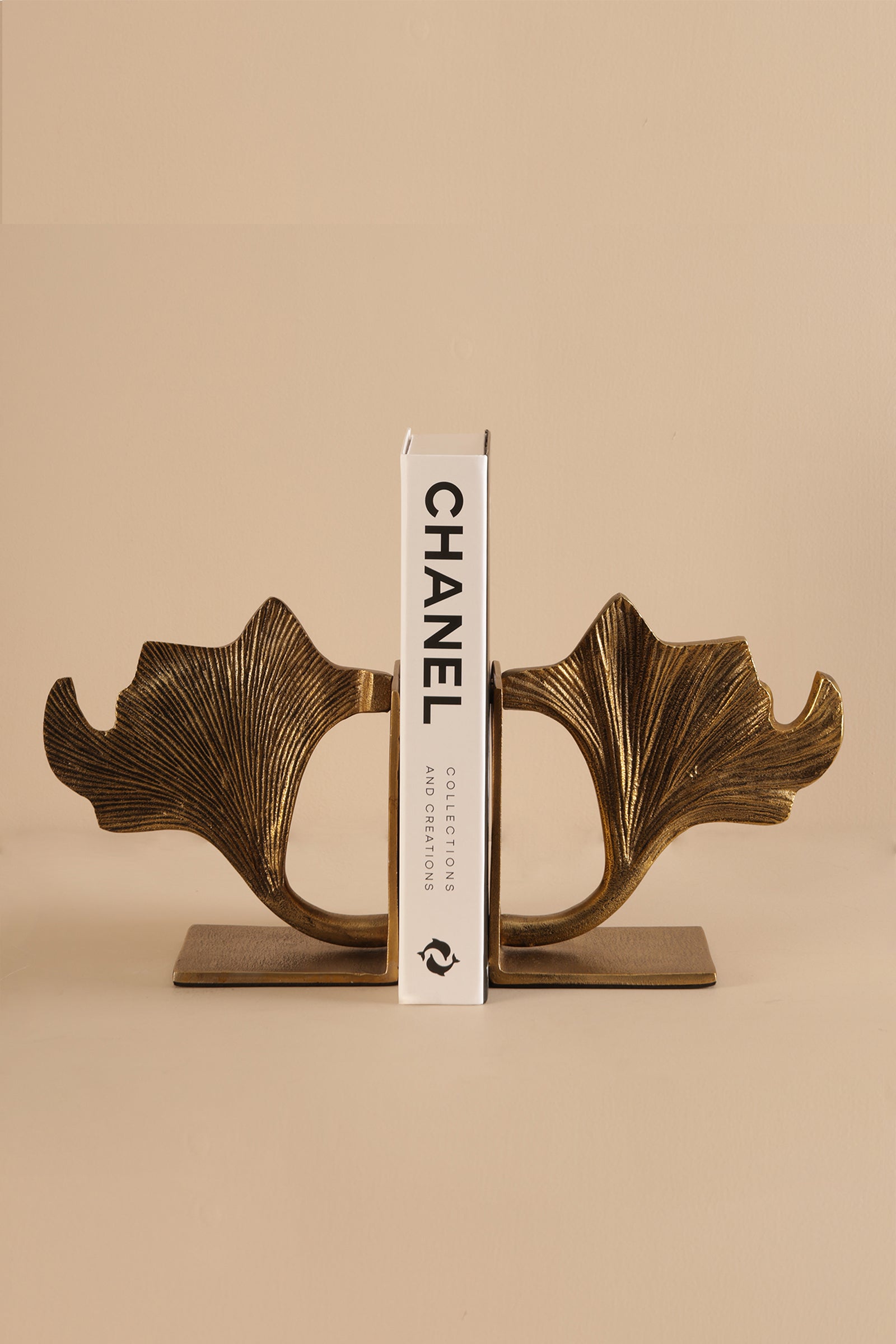 Side view of Ginco Gynco brass bookend showing curved leaf silhouette