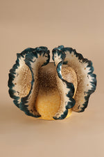 Ceramic shell-shaped bowl with scalloped edge on a beige background