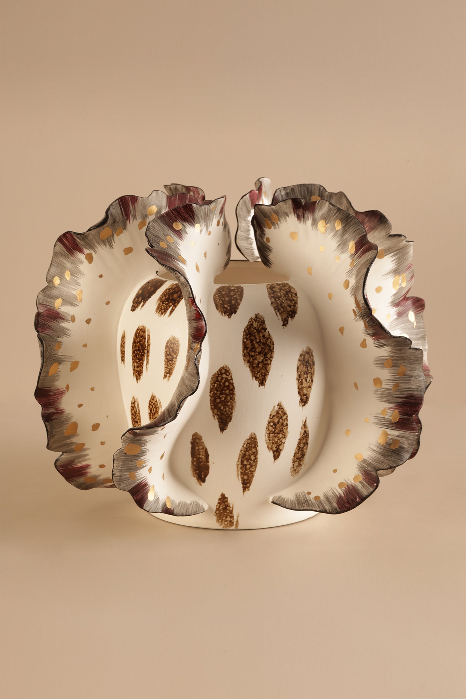Decorative ceramic plate with scalloped edge and brown speckled pattern on a beige background