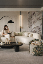 Modern living room with a woman sitting on a sofa, surrounded by stylish decor elements.