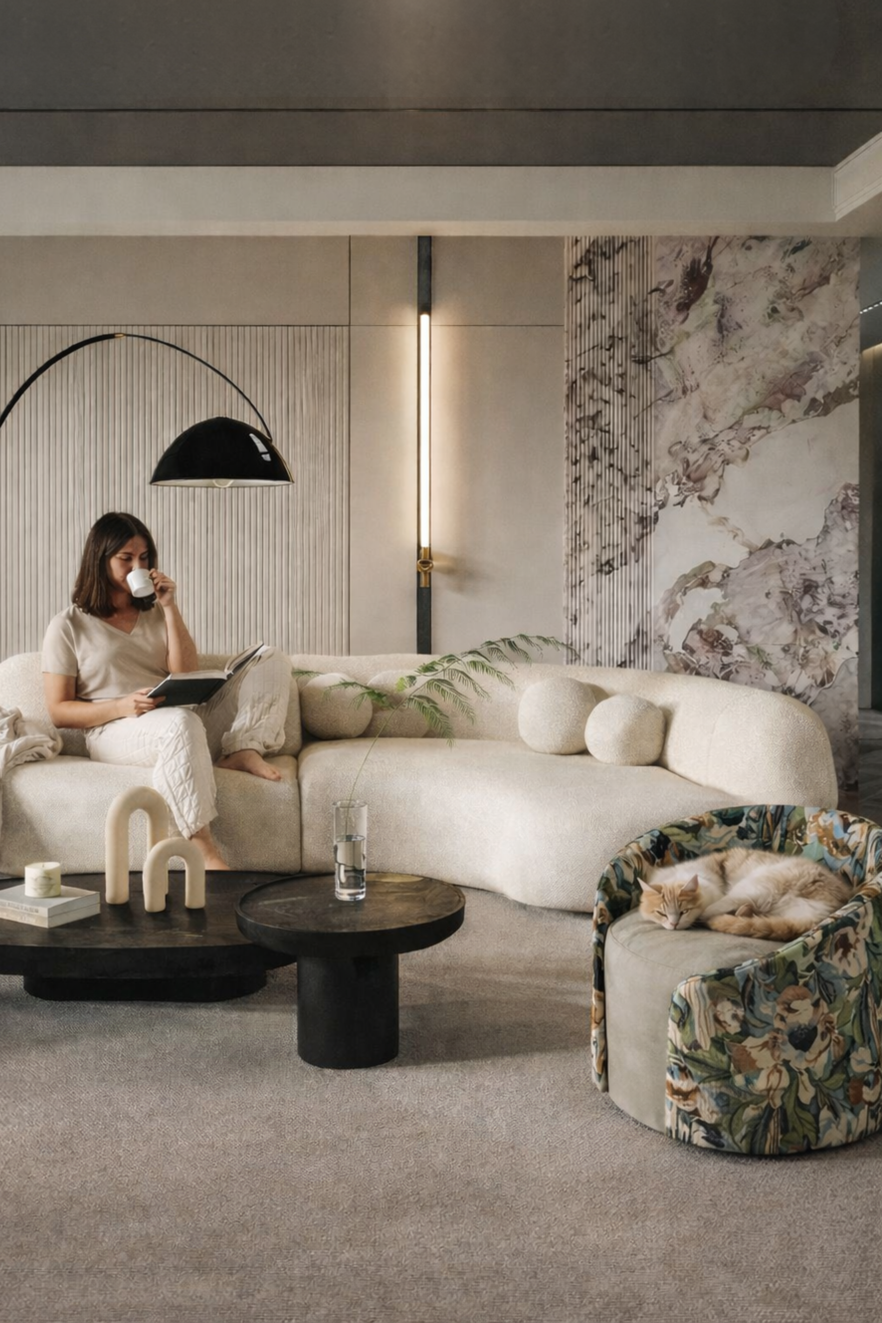 Modern living room with a woman sitting on a sofa, surrounded by stylish decor elements.