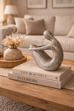 Decorative sculpture on books with 'Live Beautiful Interiors' text in a living room setting